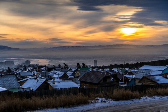 The beautiful sunset over the Selenga river valley, the wooden residential houses, and the hills of Ulan-Ude, the capital of Buryatia, Russia.