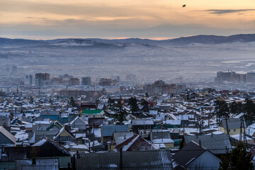 The panorama view of the wooden residential buildings and Soviet-style downtown of Ulan-Ude, Buryatia, Russia, during the winter sunset in Siberia.