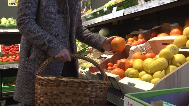 Orange einkaufen und in Einkaufskorb legen / Einkaufen Supermarkt Orangen Obst / Orange / frisches Obst einkaufen 