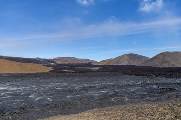 Panoramic view over landscape and lava field near mountain Fagradalsfjall, Iceland, with fissure vent of 2021 Geldingadalir volcano area against a white clouded blue sky
