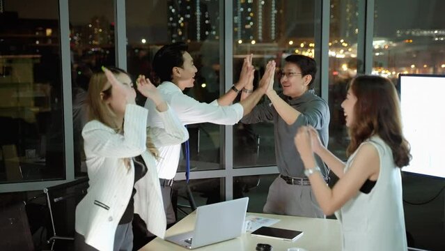 Business team meeting planning late into the night, work team doing high-five gesture to show the power of cooperation and success. business ideas, diligence, business struggle, overtime
