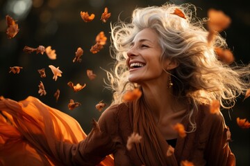 An older woman throwing fall leaves by herself on a autumn park