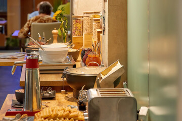 Breakfast in hotel, lighted table with different dishes, authentic situation, blurred background. 