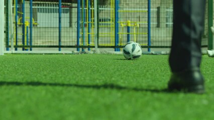 Disabled man with amputated leg kicking ball  with crutch and  scoring a goal . Close up playing football with kids on sport stadium . Physical disabled peoples rights . Hitting ball with stick 