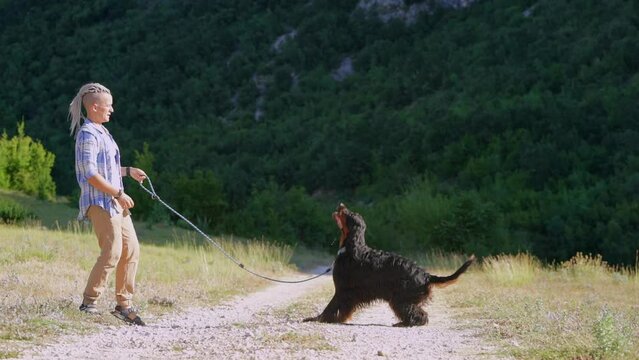 a girl in dreadlocks with dog setter Gordon the backdrop of mountains. Friendship, walking with dogs