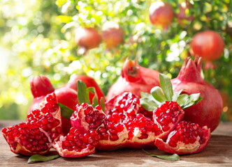 fresh ripe pomegranates on a wooden table in a garden
