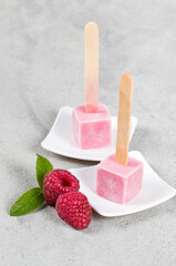 Vegan Cold dessert. Raspberry ice cream in the shape of small cube on a wooden stick. Light background