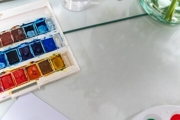 This close-up photo shows a watercolor palette. The palette is arranged in a way that makes it look...