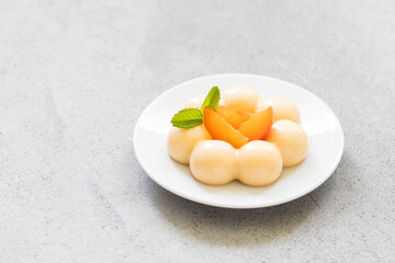 Vegan Apricot cream dessert, Panna Cotta in the shape of truffles, decorated with fresh apricot slices. On a plate. LIght grey background. Close up. Copy space