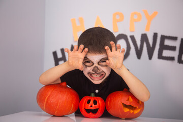 Portrait of cute kid boy making Halloween home decorations while sitting at table, happy halloween day