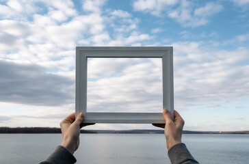 Hands holding a blank photo frame on the background of the lake