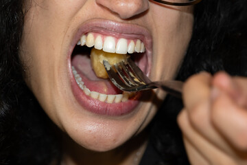 Bouche d'une femme en gros plan en train de manger avec une fourchette - obrazy, fototapety, plakaty