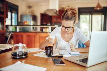 Young woman going over her financials in the kitchen of her home