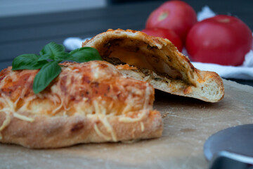 Delicious pizza calzone with tomato souse and cheese on wooden plate