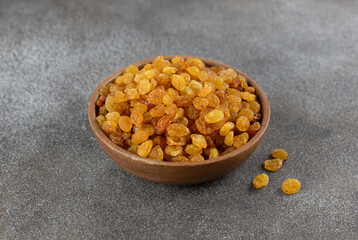 Bowl of golden raisins on a gray background. 