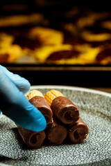 Primer plano del chef sosteniendo obleas enrolladas con chocolate.