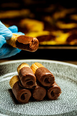 Primer plano del chef sosteniendo obleas enrolladas con chocolate.