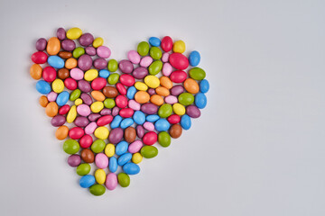 Multi-colored heart-shaped candies on a light background. Candy dragees. Candy background