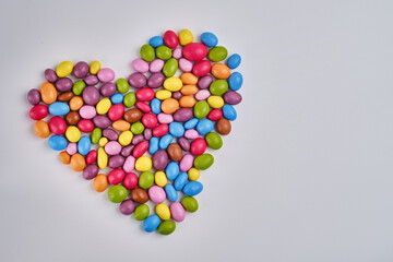 Multi-colored heart-shaped candies on a light background. Candy dragees. Candy background