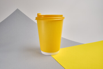 Disposable yellow paper cup on a light background. Mock up 
