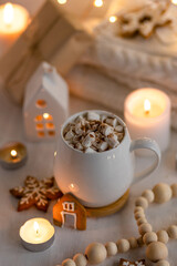 Obraz na płótnie Canvas Winter delicious gourmet christmashot drink. Chocolate or cocoa with marshmallow and spices on white background. Gingerbread cookies, candles. Cozy home atmosphere, festive vibes