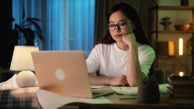Portrait of exhausted young asian woman with head on her hands feeling upset while take a break at home Tired female with failed ideas creative block or lack of inspiration indoors