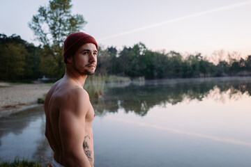 Fototapeta premium Serious guy walking at the forest near the water and preparing for the swimming in the cold lake 