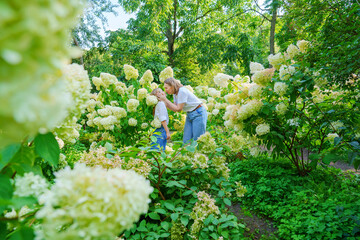 mother and daughter in flowering hydrangea bushes.