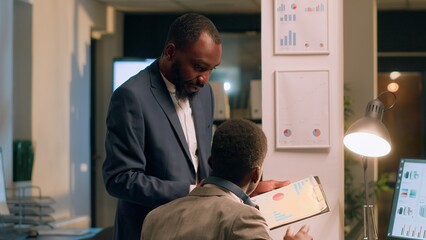 Office manager interrupting distracted worker listening to music while checking statistical graphs...