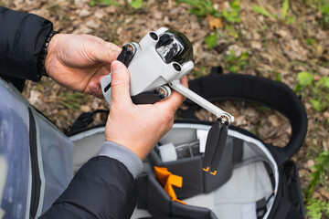 Male hands prepare a mini drone with a camera for flight.