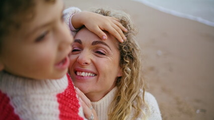 Closeup mother hugging child at ocean shore. Smiling woman looking kid with love