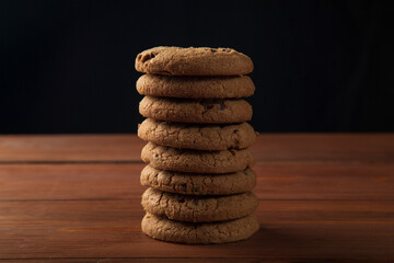 Oatmeal cookies with chocolate on the table and on a dark background.