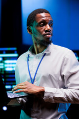 African american expert troubleshooting server farm providing vast computing resources and storage. High tech facility enabling artificial intelligence to process massive datasets for training