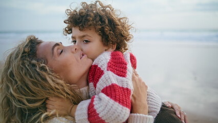 Fototapeta na wymiar Happy mother cuddling son at autumn ocean shore closeup. Sincere family emotions