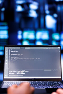 Close up shot of developers updating server rigs, writing complex binary code scripts on laptop. Programmers using JavaScript, Java, and database programming to fortify cybersecurity in data center