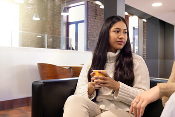 Young woman with native American features drinking a coffee in cafe. Copyspace.