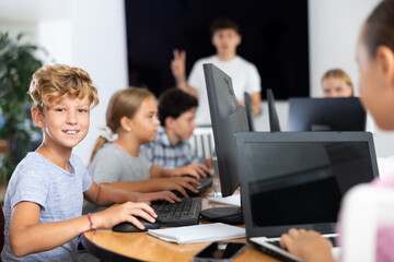 Fototapeta premium Boy student learning to use computer in group in classroom