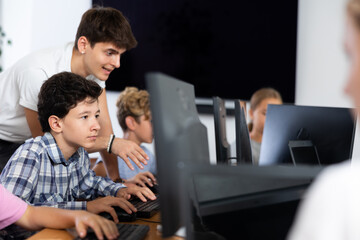 Concerned preteen boy sitting at computer while trainer explaining him something during IT courses