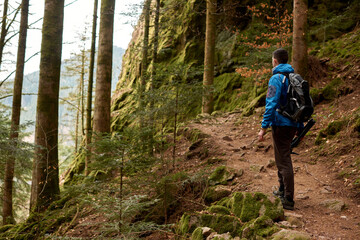 Fototapeta premium Traveler Man with backpack mountaineering Travel Lifestyle concept mountains on background Summer trip vacations outdoor. Concept of travel and healthy, active lifestyle. Young guy with dreadlocks