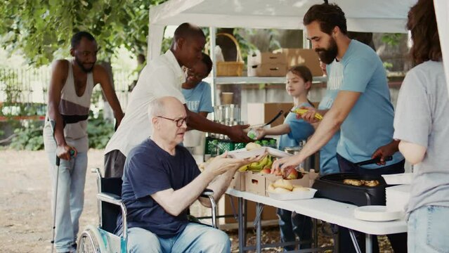 Voluntary individuals donate free food to needy offering helping hand in fight against hunger and poverty. Volunteers providing humanitarian aid to the poor homeless and handicapped people. Handheld.