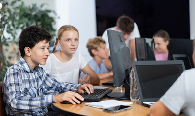Computer science lesson in a school computer class - a girl and a boy solve problems on the...