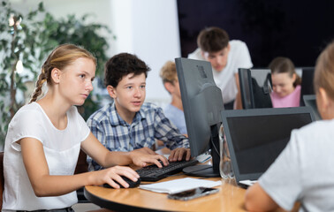 Concerned preteen girl and boy working together on computer in IT training room