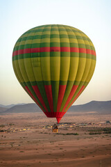 Hot balloon flying at sunset over the Atlas Mountains in the desert of Morocco 