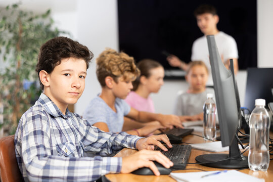 Boy student learns to work with computer in group at lesson