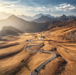 Aerial view of road in mountain valley, golden sunlight at sunset in autumn. Passo Giau, Dolomites,...