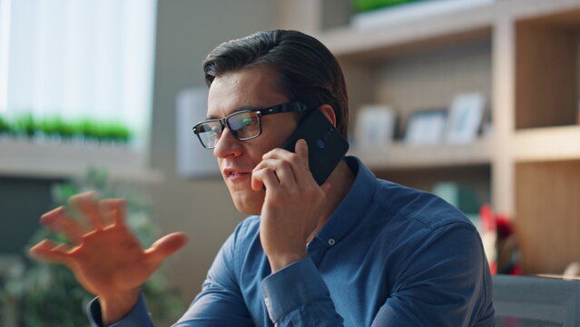 Stressed man disputing telephone call at work room close up. Businessman arguing