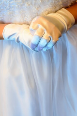 Hands of a girl in a white dress during a First Communion religious event. 