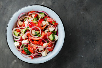 Fresh vegetable salad with feta cheese on dark concrete background. Top view. Copy space