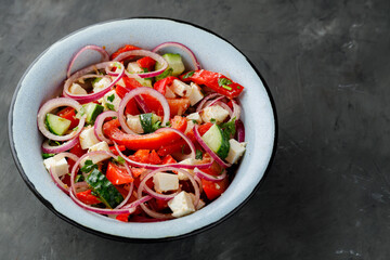Fresh vegetable salad with feta cheese on dark concrete background. Top view. Copy space