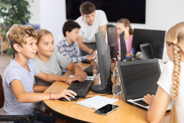 Fototapeta premium Computer science lesson in a school computer class - a girl and a boy solve problems on the computer together
